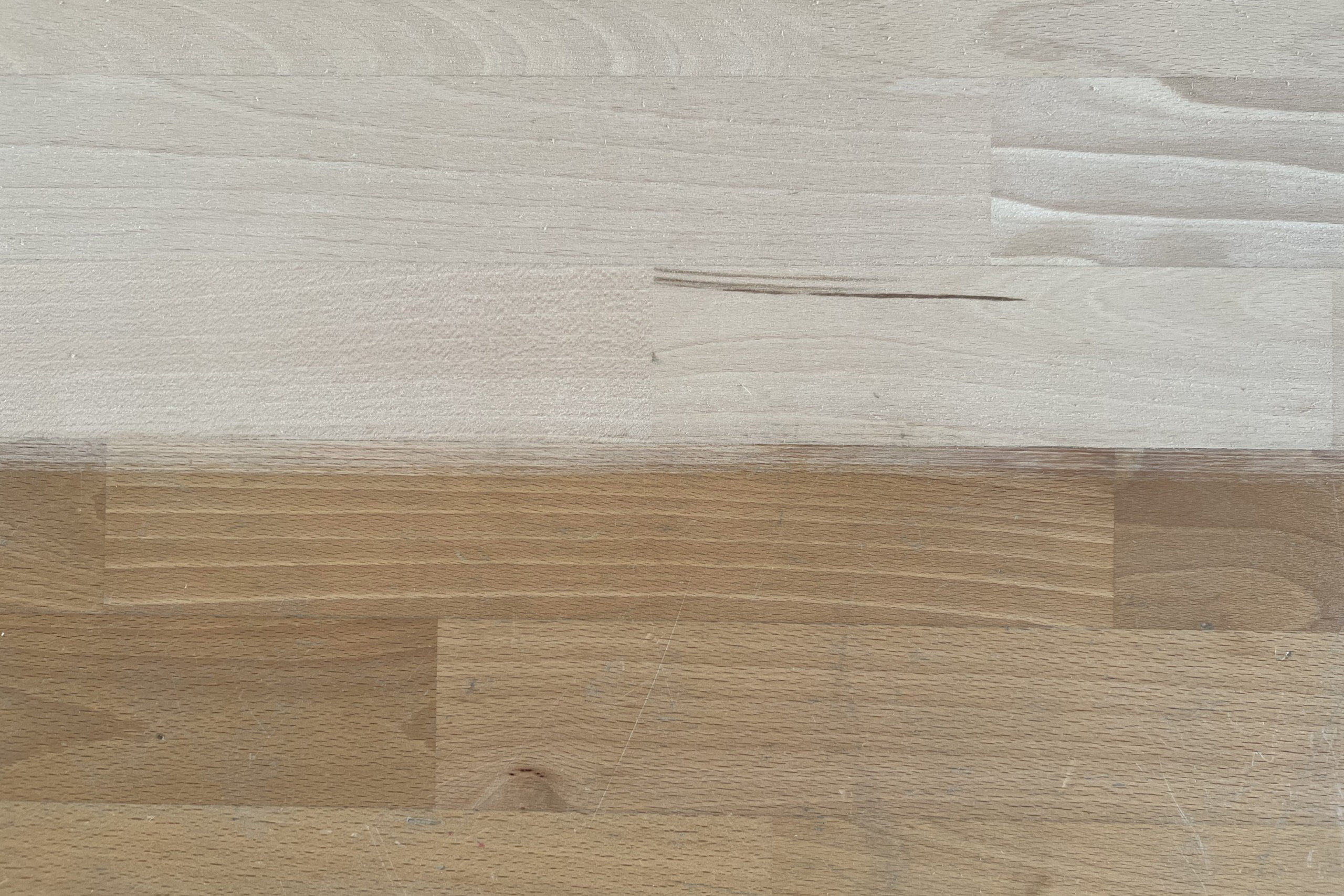 Nahaufnahme eines Holzbodens mit sichtbarem Farbunterschied zwischen aufgearbeiteter und ursprünglicher Fläche